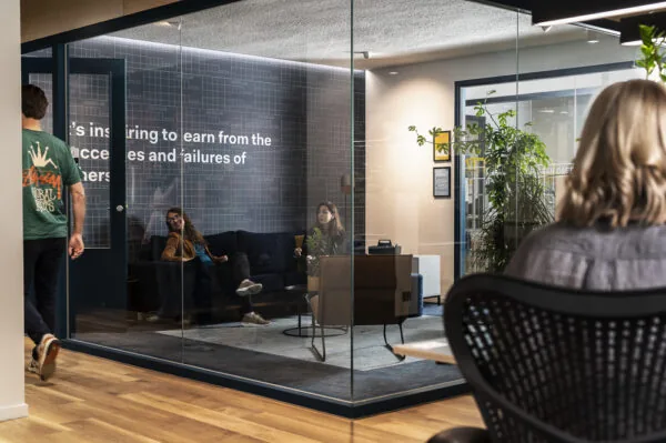 Modern kantoorinterieur aan de Aert van Nesstraat met mensen in gesprek in een glazen vergaderruimte.